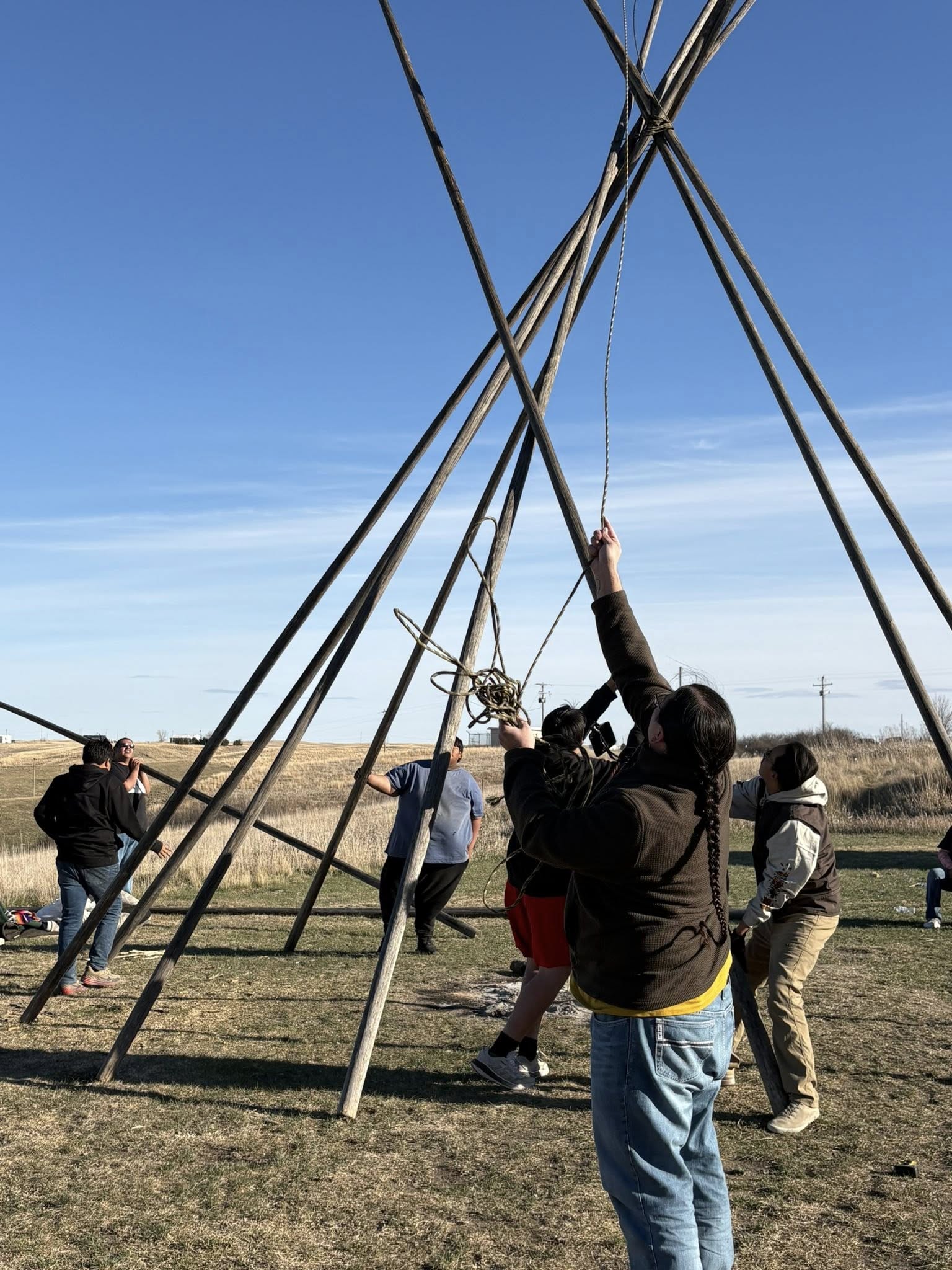 Community members at Pine Ridge raising the tipi poles together